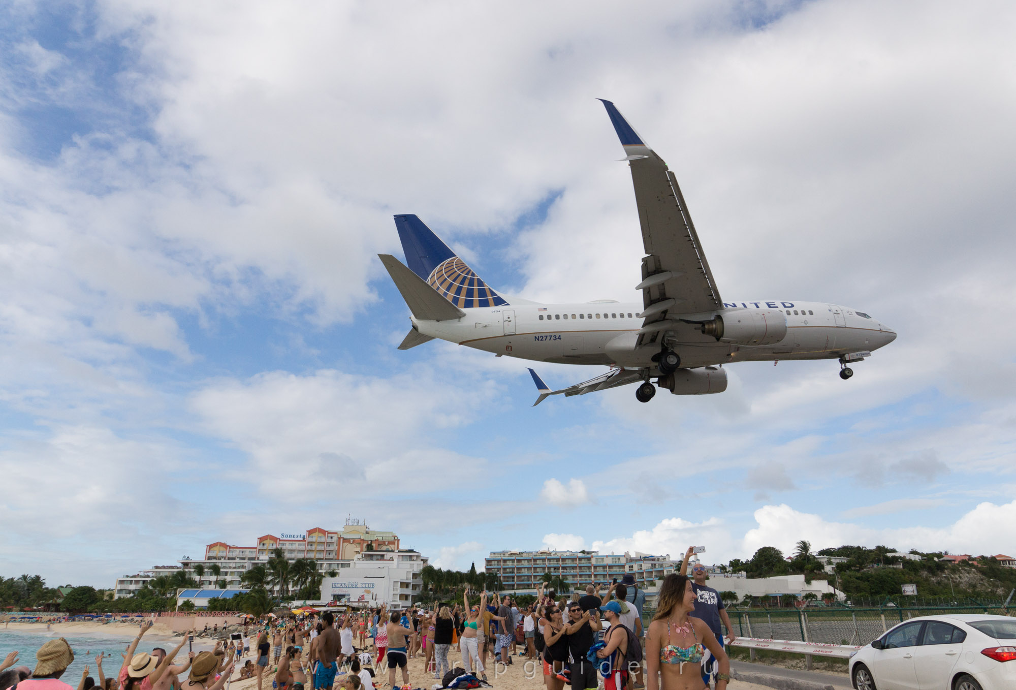 Самолет Boeing 737-724 авиакомпании United над пляжем Синт-Мартена Самолет Boeing 737-724 авиакомпании United над пляжем Синт-Мартена